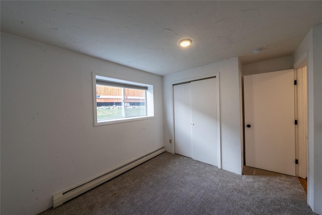 unfurnished bedroom with carpet flooring, a closet, and baseboard heating