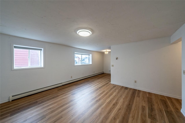 basement featuring a baseboard heating unit and hardwood / wood-style floors