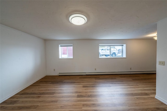 empty room with a baseboard heating unit and dark hardwood / wood-style floors