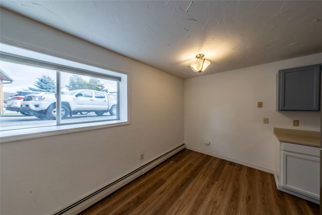 unfurnished dining area with dark wood-type flooring and baseboard heating