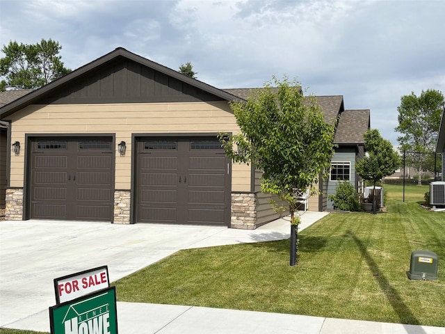 217 Palmer Dr, Kalispell, MT 59901 - view of front of home featuring stone siding, concrete driveway, a front yard, a shingled roof, and a garage
