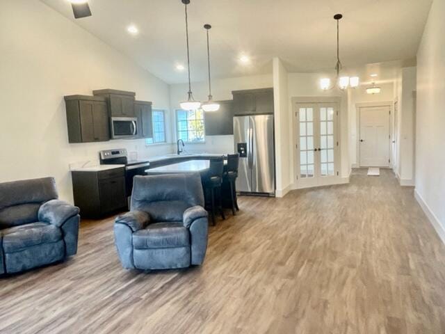 kitchen featuring stainless steel appliances, sink, pendant lighting, and light hardwood / wood-style flooring