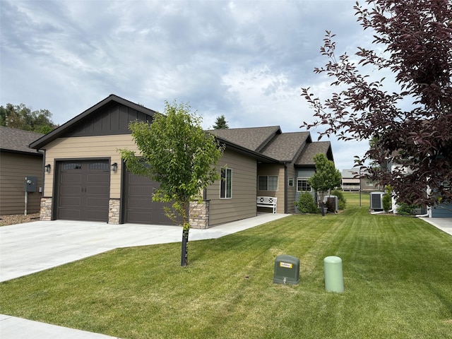 217 Palmer Dr, Kalispell, MT 59901 - craftsman inspired home featuring driveway, an attached garage, roof with shingles, a front yard, and stone siding