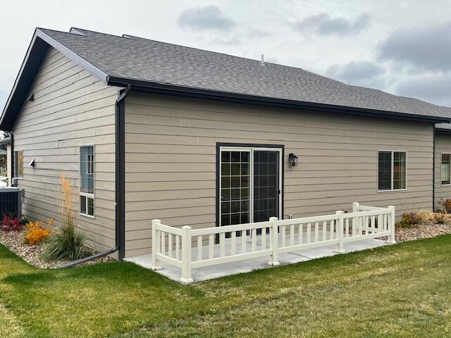 rear view of property with cooling unit and a yard