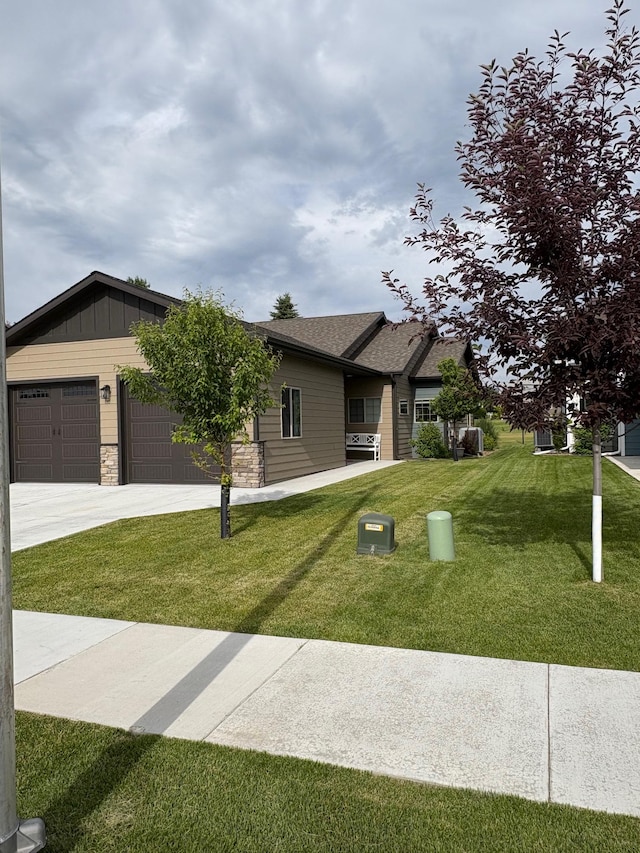 217 Palmer Dr, Kalispell, MT 59901 - view of front facade with a front lawn, stone siding, driveway, and an attached garage