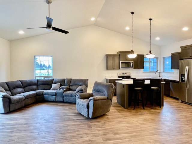 living room with ceiling fan, high vaulted ceiling, sink, and light wood-type flooring