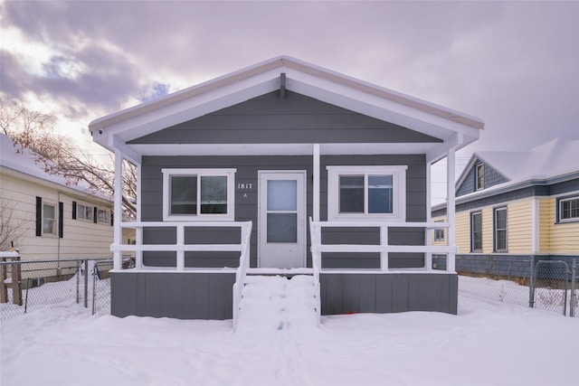 snow covered back of property featuring fence and a carport