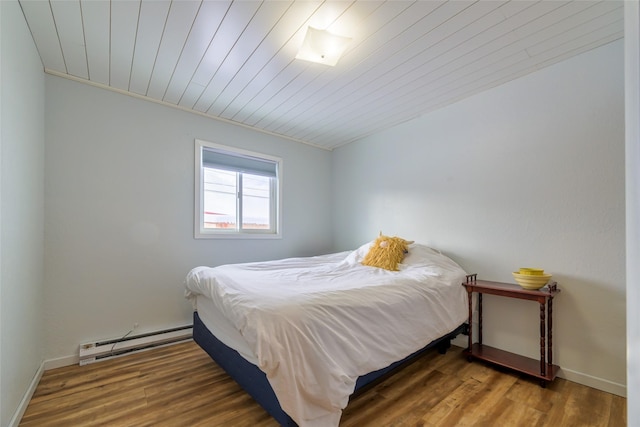 bedroom with wooden ceiling, baseboards, baseboard heating, and wood finished floors