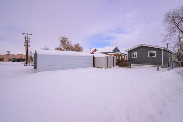 yard layered in snow featuring a shed