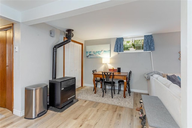 dining room featuring a wood stove, light wood finished floors, and baseboards