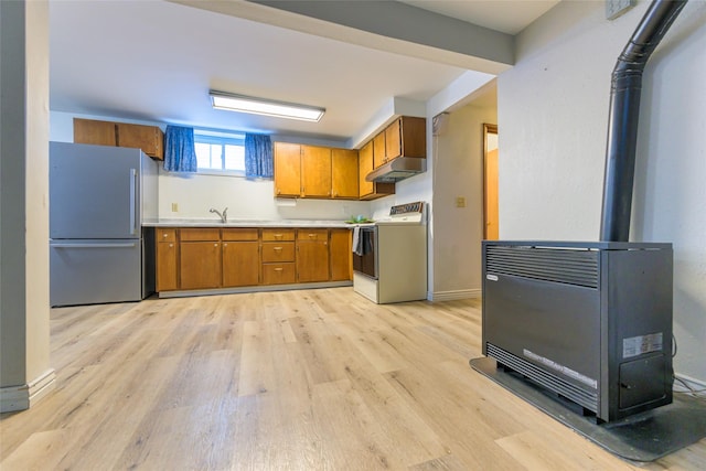 kitchen with heating unit, range, a wood stove, stainless steel fridge, and light hardwood / wood-style floors