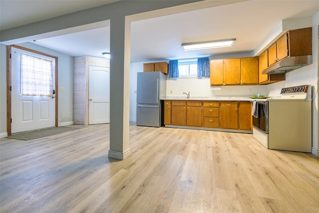 kitchen featuring stove, sink, stainless steel refrigerator, and light wood-type flooring