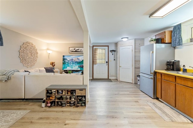 kitchen featuring light wood-type flooring, a sink, freestanding refrigerator, and brown cabinets