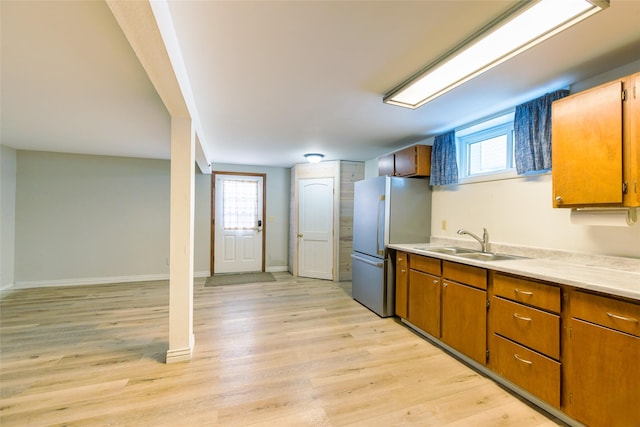 kitchen with a wealth of natural light, light wood-type flooring, a sink, and freestanding refrigerator