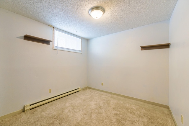 spare room featuring baseboard heating, light carpet, and a textured ceiling