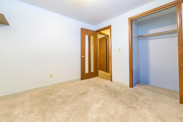 unfurnished bedroom with a closet, light carpet, and a textured ceiling