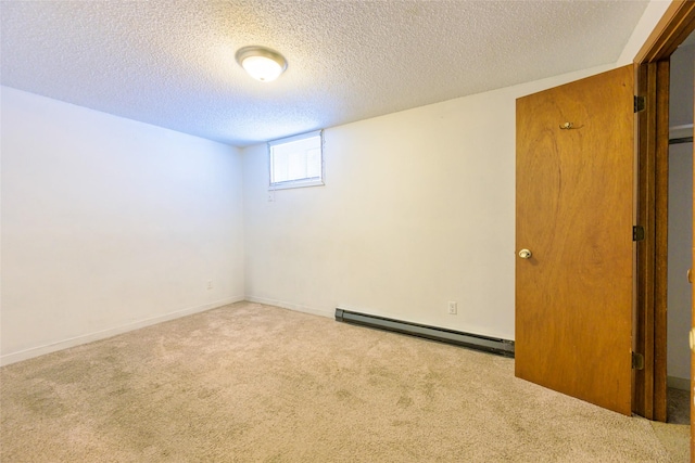 carpeted spare room featuring a baseboard heating unit and a textured ceiling