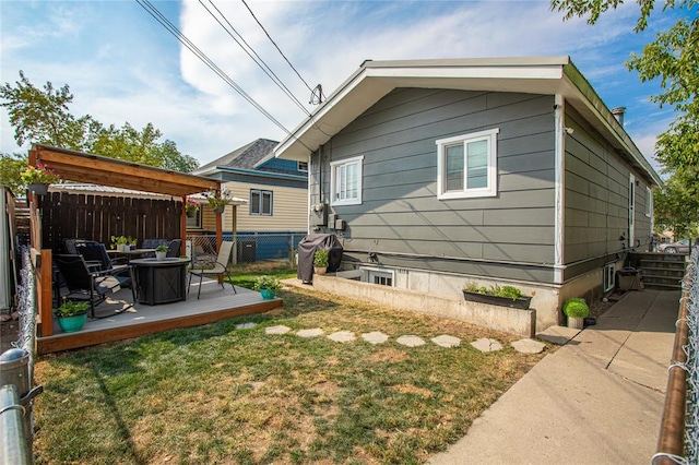 back of property featuring fence, a wooden deck, and a lawn