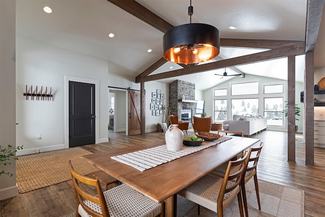 dining space featuring beam ceiling, dark wood-type flooring, and a barn door