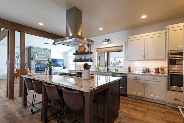 kitchen featuring vaulted ceiling with beams, light stone counters, island range hood, a center island, and white cabinets