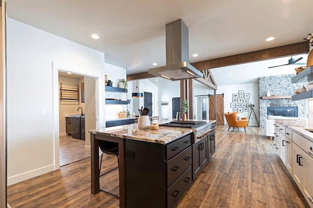 kitchen with a center island, light stone countertops, white cabinets, island exhaust hood, and stainless steel gas stovetop