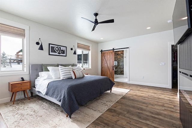 bedroom featuring a barn door, hardwood / wood-style floors, and ceiling fan