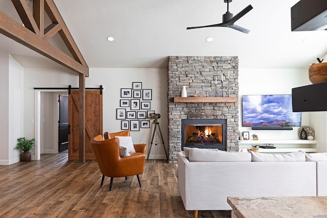 living room featuring ceiling fan, dark hardwood / wood-style floors, a fireplace, vaulted ceiling, and a barn door