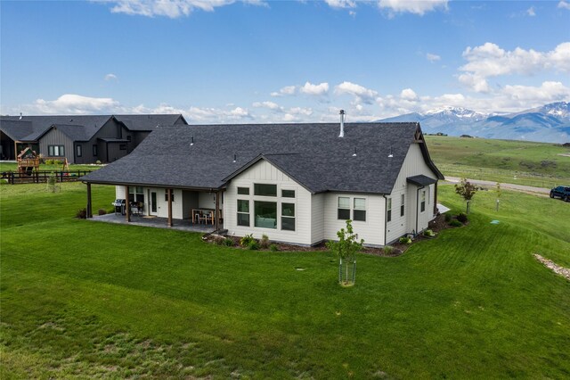 back of house with a mountain view, a yard, and a patio area