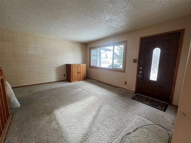 entryway featuring light carpet, baseboards, and a textured ceiling