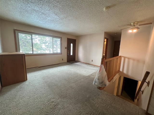 spare room featuring a textured ceiling, carpet, and baseboards