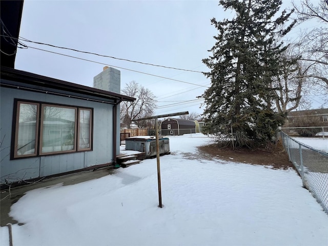 snowy yard with a jacuzzi and fence