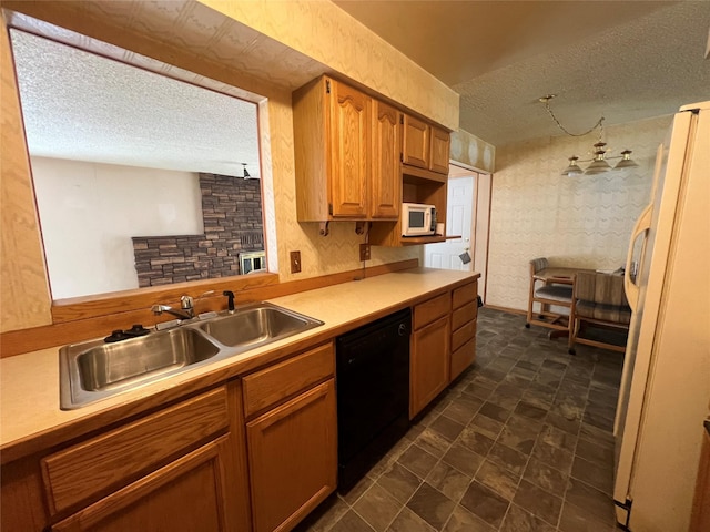 kitchen with white appliances, brown cabinetry, light countertops, a textured ceiling, and a sink