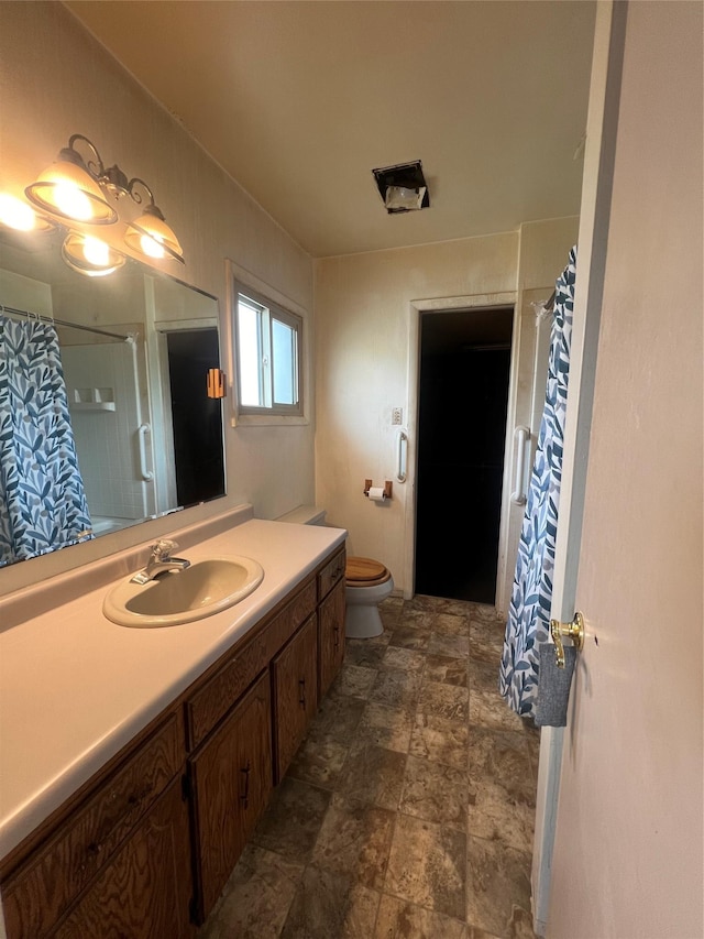 bathroom with curtained shower, stone finish flooring, vanity, and toilet