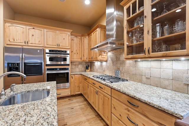 kitchen with sink, ventilation hood, stainless steel appliances, light stone countertops, and light hardwood / wood-style floors