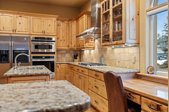 kitchen featuring wall chimney exhaust hood, light stone counters, tasteful backsplash, a kitchen island, and stainless steel appliances