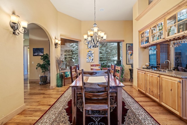 dining space with sink, a notable chandelier, and light wood-type flooring