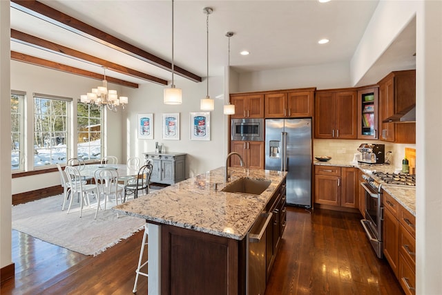 kitchen featuring sink, hanging light fixtures, high quality appliances, a kitchen island with sink, and wall chimney range hood