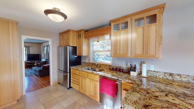 kitchen with appliances with stainless steel finishes, sink, light brown cabinetry, and light stone counters