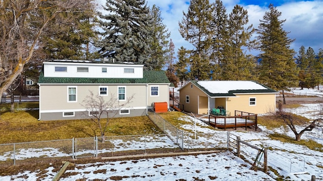 snow covered back of property with a deck