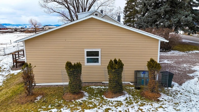 snow covered property with a mountain view and central AC unit