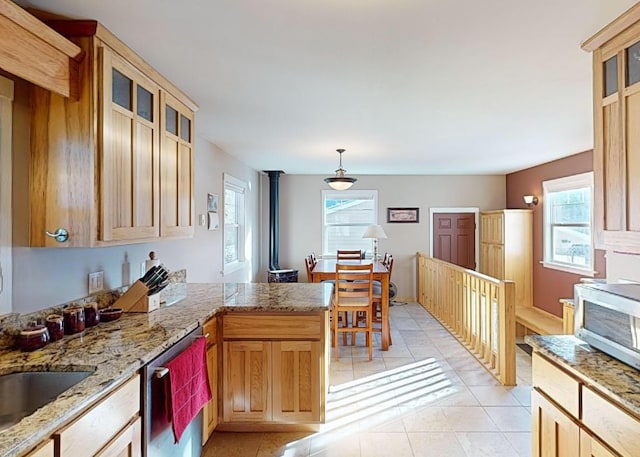 kitchen featuring light tile patterned flooring, a wood stove, appliances with stainless steel finishes, kitchen peninsula, and pendant lighting