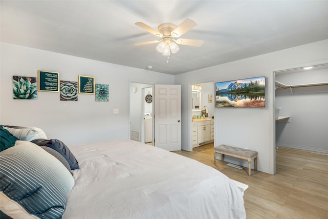 bedroom featuring a spacious closet, connected bathroom, ceiling fan, and light hardwood / wood-style flooring