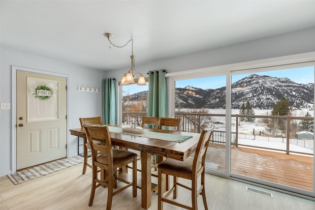 dining space featuring an inviting chandelier, a mountain view, and light hardwood / wood-style floors