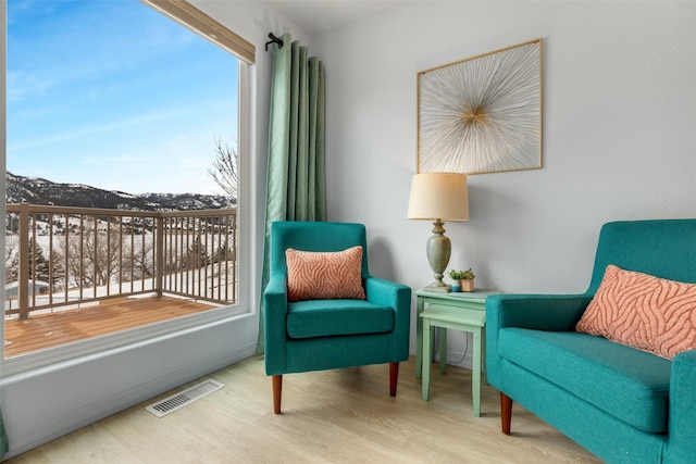 sitting room featuring a mountain view, light hardwood / wood-style floors, and a healthy amount of sunlight