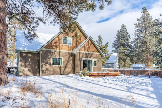 snow covered back of property with a deck