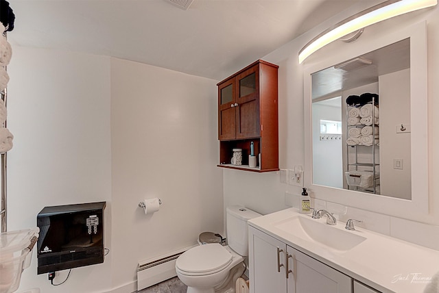 half bathroom featuring toilet, baseboard heating, and vanity