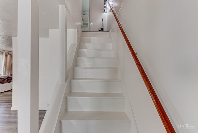 staircase featuring a textured ceiling and wood finished floors