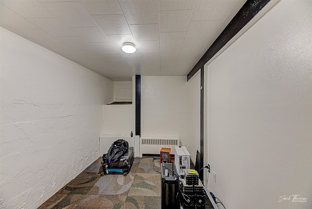 workout area featuring carpet, a textured wall, and radiator heating unit