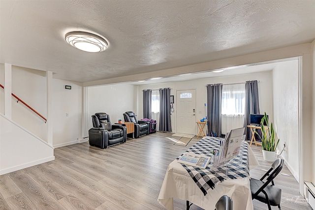 living area with light wood-style floors, stairs, baseboards, and a textured ceiling