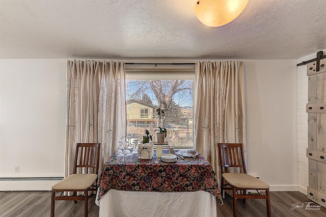 dining area featuring a barn door, baseboards, wood finished floors, a textured ceiling, and a baseboard heating unit